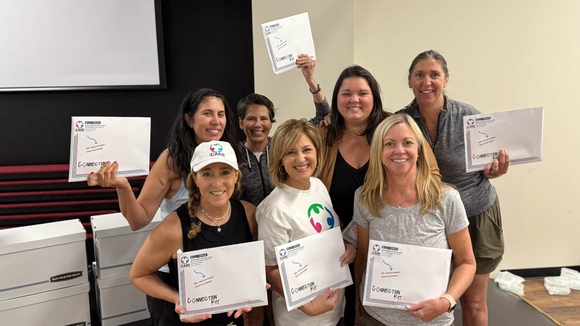 iCARE Adoptive And Foster Families volunteers and educators smiling and holding Connection Kits™ at a community training volunteer event