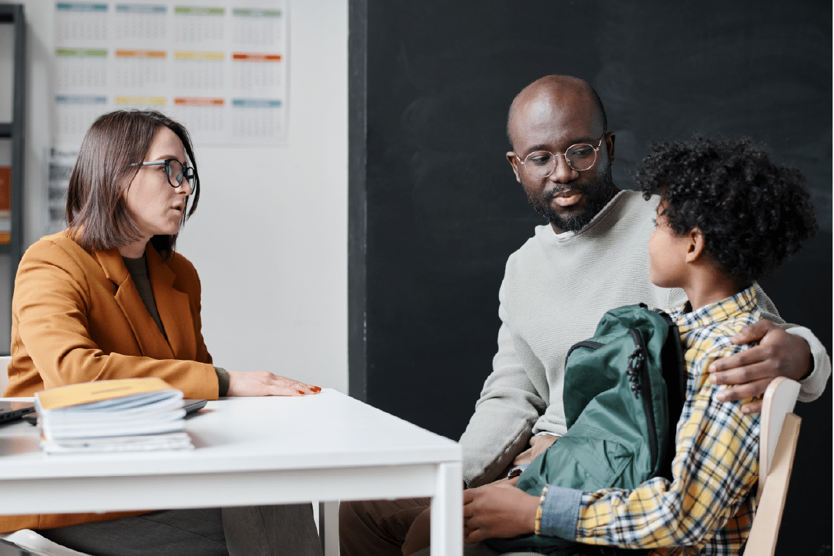 “School professional meeting with a caregiver and teenage student, demonstrating collaborative support and partnership.”