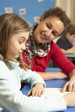 Schoolgirl Studying In Classroom With Teacher
